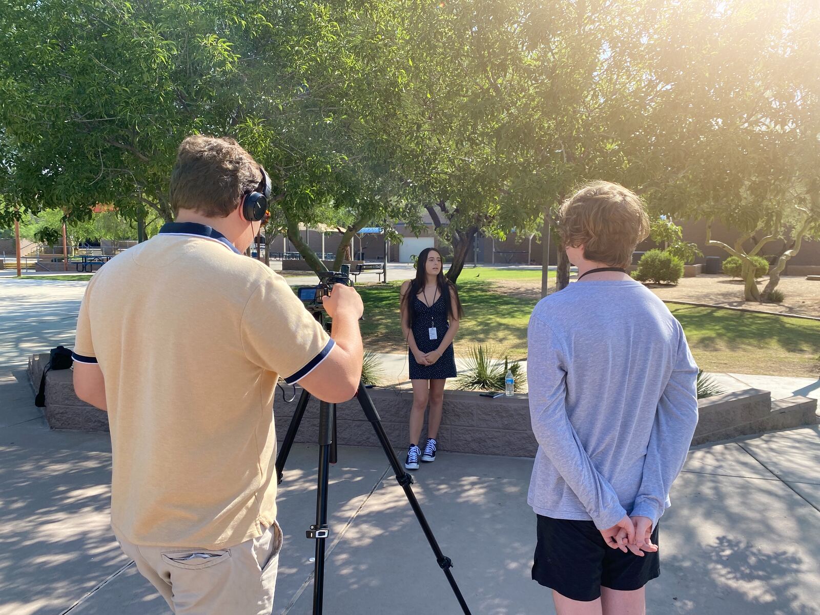 Student filming an interview under a tree