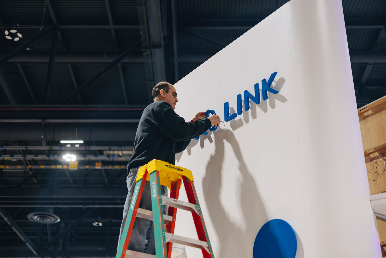 Installer lettering a wall from a ladder